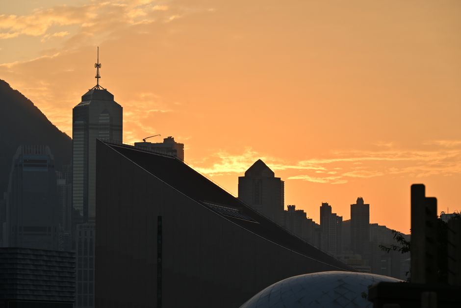 City skyline silhouette at sunset with warm orange sky.